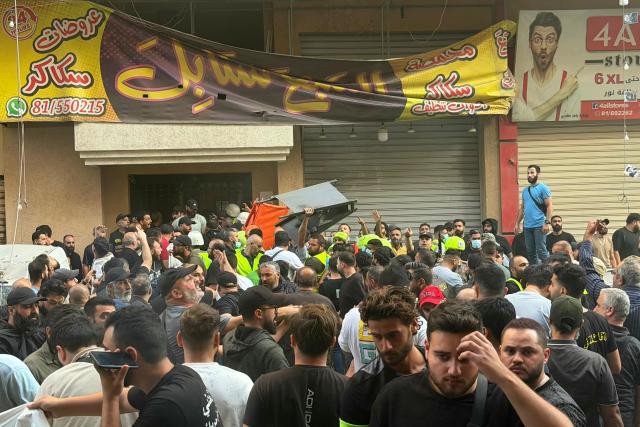 People gather as rescuers arrive at the scene following an Israeli military strike targeting a residential building in the Haret Hreik neighbourhood, of Beirut's southern suburbs on November 23, 2025. Israel's military said on November 23, 2025, that it had carried out a strike on a senior member of the Iran-backed Hezbollah militant group in Lebanon's capital. (Photo by Ibrahim AMRO / AFP)