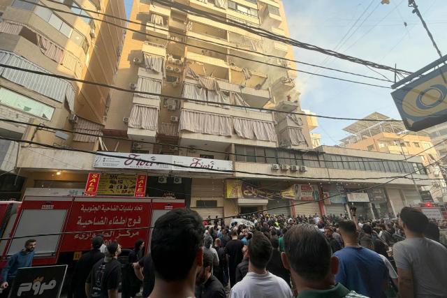 People gather looking at a residential building following an Israeli military strike in the Haret Hreik neighbourhood, of Beirut's southern suburbs on November 23, 2025. Israel's military said on November 23, 2025, that it had carried out a strike on a senior member of the Iran-backed Hezbollah militant group in Lebanon's capital. (Photo by Ibrahim AMRO / AFP)