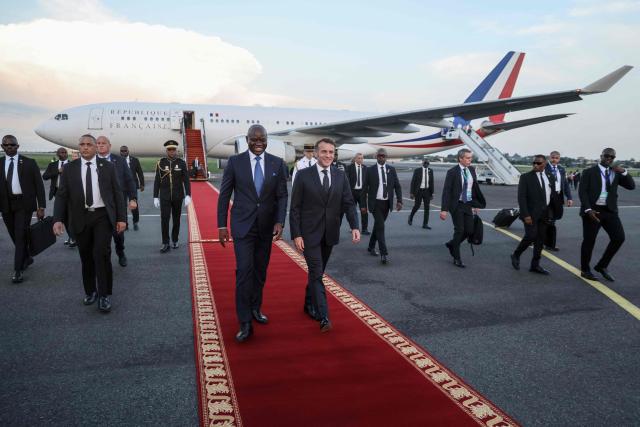 TOPSHOT - France’s President Emmanuel Macron (CR) is welcomed by Gabon's President Brice Oligui Nguema (CL) upon Macron's arrival at the Leon-Mba International Airport in Libreville on November 23, 2025. (Photo by Ludovic MARIN / AFP)