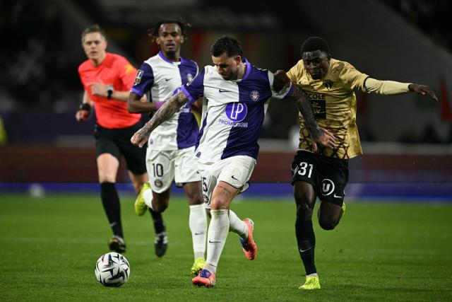 Toulouse's Norwegian midfielder #15 Aron Donnum (C) fights for the ball with Angers' cameroonian defender #31 Harouna Djibirin during the French L1 football match between Toulouse FC and Angers SCO at the TFC Stadium in Toulouse, southwestern France, on November 23, 2025. (Photo by Lionel BONAVENTURE / AFP)