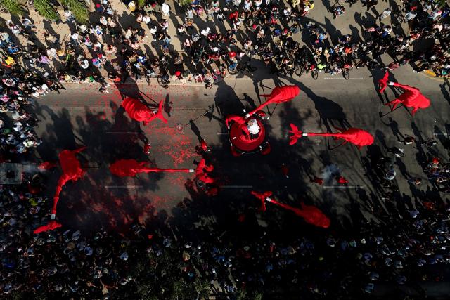 TOPSHOT - This aerial view shows artists maneuvering giant giraffe puppets during the French street theatre group Compagnie OFF’s “Les Girafes – Operette Animaliere” in Guadalajara, Jalisco, Mexico on November 23, 2025. The show, a blend of opera, circus arts, dance, and performance, was presented as part of the Late 2025 Festival of Cultura GDL, which took place in the streets of Guadalajara. (Photo by ULISES RUIZ / AFP)