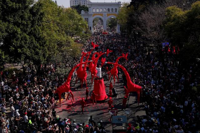 This aerial view shows artists maneuvering giant giraffe puppets during the French street show “Les Girafes – Operette Animaleиre” in Guadalajara, Jalisco, Mexico on November 23, 2025. “Les Girafes – Operette Animaliere,” a show blending opera, circus arts, dance, and performance art, was presented as part of the late-2025 Festival de Cultura GDL, which took place in the streets of Guadalajara. (Photo by ULISES RUIZ / AFP)