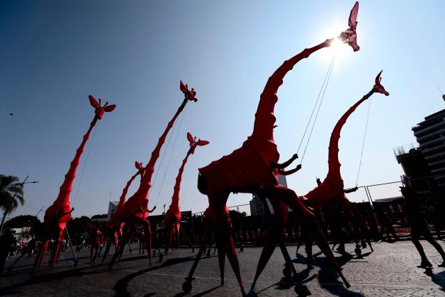 Artists perform amid giant giraffe puppets during the French street theatre group Compagnie OFF’s “Les Girafes – Operette Animaliere” in Guadalajara, Jalisco, Mexico on November 23, 2025. The show, a blend of opera, circus arts, dance, and performance, was presented as part of the Late 2025 Festival of Cultura GDL, which took place in the streets of Guadalajara. (Photo by ULISES RUIZ / AFP)
