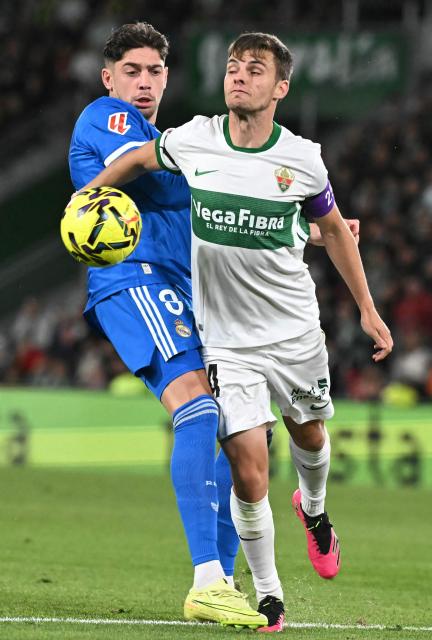 Real Madrid's Uruguayan midfielder #08 Federico Valverde fights for the ball with Elche's Spanish midfielder #14 Aleix Febas during the Spanish league football match between Elche CF and Real Madrid CF at Martinez Valero Stadium in Elche on November 23, 2025. (Photo by JOSE JORDAN / AFP)