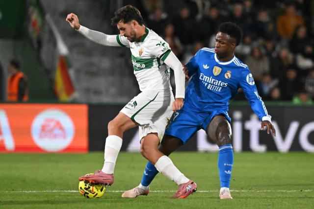 Elche's Spanish defender #23 Victor Chust (L) fights for the ball with Real Madrid's Brazilian forward #07 Vinicius Junior during the Spanish league football match between Elche CF and Real Madrid CF at Martinez Valero Stadium in Elche on November 23, 2025. (Photo by JOSE JORDAN / AFP)