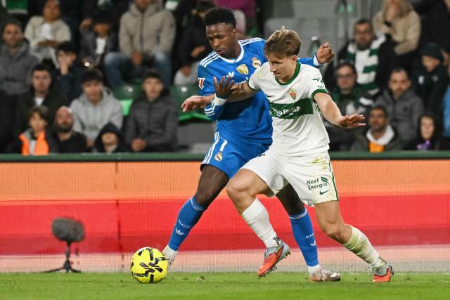 Real Madrid's Brazilian forward #07 Vinicius Junior (L) fights for the ball with Elche's Austrian defender #22 David Affengruber during the Spanish league football match between Elche CF and Real Madrid CF at Martinez Valero Stadium in Elche on November 23, 2025. (Photo by JOSE JORDAN / AFP)