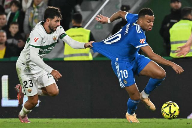 Elche's Spanish defender #23 Victor Chust grasps the jersey of Real Madrid's French forward #10 Kylian Mbappe during the Spanish league football match between Elche CF and Real Madrid CF at Martinez Valero Stadium in Elche on November 23, 2025. (Photo by JOSE JORDAN / AFP)