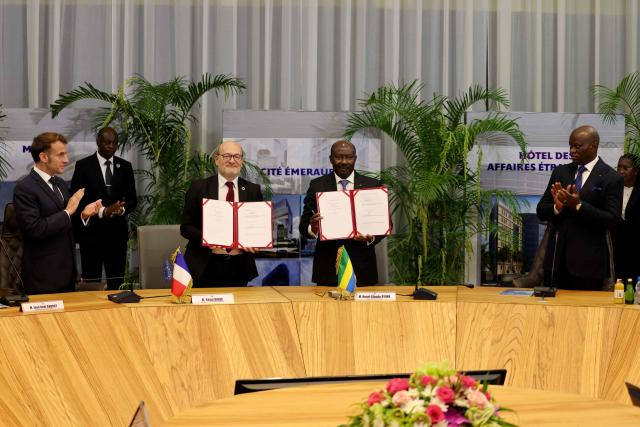 Gabon's Economy minister Henri-Claude Oyima (2nd L) and France's Chief Executive Officer of Agence Française de Developpement (AFD - French Development Agency) Remy Rioux (2nd L) pose after signing a contract on a railway planned reconstruction, as Gabon's President Brice Oligui Nguema (R) and France's President Emmanuel Macron (L) attend following their meeting in Libreville on November 23, 2025. (Photo by Ludovic MARIN / AFP)