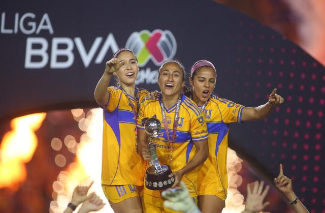 Tigres' defender #04 Greta Espinoza, forward #09 Stephany Mayor and defender #15 Cristina Ferral celebrate with the trophy after winning the Liga MX Femenil Apertura final second leg football match between Tigres and America at the Universitario Stadium in Monterrey, Nuevo Leon state, Mexico on November 23, 2025. (Photo by Julio Cesar AGUILAR / AFP)