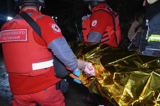 EDITORS NOTE: Graphic content / TOPSHOT - Paramedics carry the body of a victim at the site of a Russian drone strike in Kharkiv late on November 23, 2025, amid the Russian invasion of Ukraine. A Russian drone strike on the major Ukrainian city of Kharkiv killed four people and wounded 17 on November 23, its mayor said. The attack came as US, Ukrainian and European officials were in Geneva to discuss a proposal to end the nearly four-year war in Ukraine, which began when Russia launched a full-scale invasion. (Photo by SERGEY BOBOK / AFP)