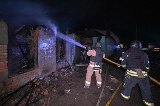 Ukrainian firefighters extinguish a fire in a house at the site of a Russian drone strike in Kharkiv late on November 23, 2025, amid the Russian invasion of Ukraine. A Russian drone strike on the major Ukrainian city of Kharkiv killed four people and wounded 17 on November 23, its mayor said. The attack came as US, Ukrainian and European officials were in Geneva to discuss a proposal to end the nearly four-year war in Ukraine, which began when Russia launched a full-scale invasion. (Photo by SERGEY BOBOK / AFP)