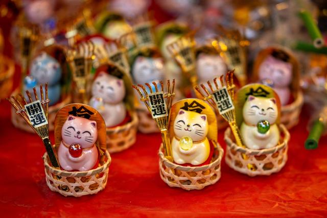 Cat figures holding "kumade", a traditional bamboo rake for good fortune, are pictured at the Hanazono Shrine during the Tori-no-Ichi festival, a traditional bamboo rakes fair for better sales and business result to the next year, at the shrine's premises in Tokyo's Shinjuku district on November 24, 2025. (Photo by Philip FONG / AFP)
