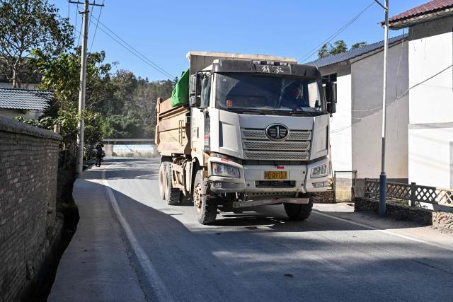 A truck heading away from a rare earth mine drives past in Anyuan county, Ganzhou, in eastern China's Jiangxi province on November 21, 2025. (Photo by Hector RETAMAL / AFP)