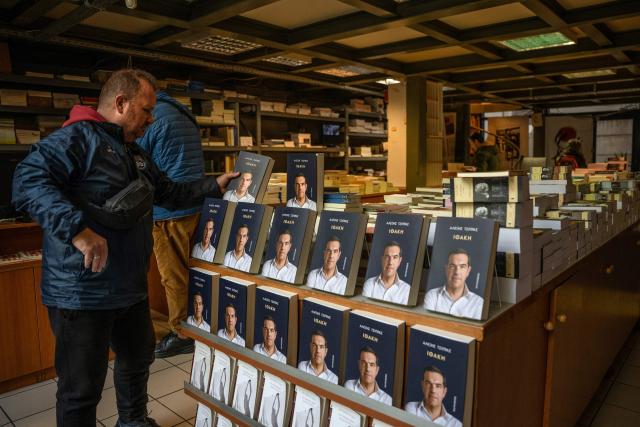 A man places the new book by Greek former Prime Minister Alexis Tsipras on display in a bookshop in Athens, on the day of its release on November 24, 2025. Greek former Prime Minister Alexis Tsipras published a long-awaited memoir ten years after a traumatic management of the country's debt crisis, as he reportedly mulls a political comeback. (Photo by Angelos TZORTZINIS / AFP)
