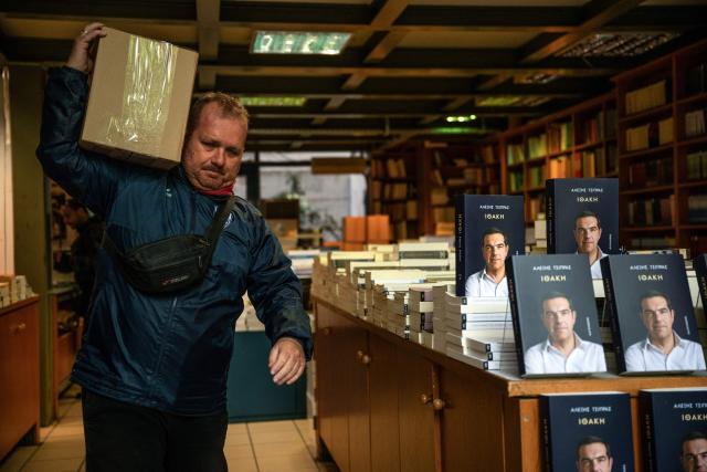A man carries a cardboard box with new book by Greek former Prime Minister Alexis Tsipras in a bookshop in Athens, on the day of its release on November 24, 2025. Greek former Prime Minister Alexis Tsipras published a long-awaited memoir ten years after a traumatic management of the country's debt crisis, as he reportedly mulls a political comeback. (Photo by Angelos TZORTZINIS / AFP)