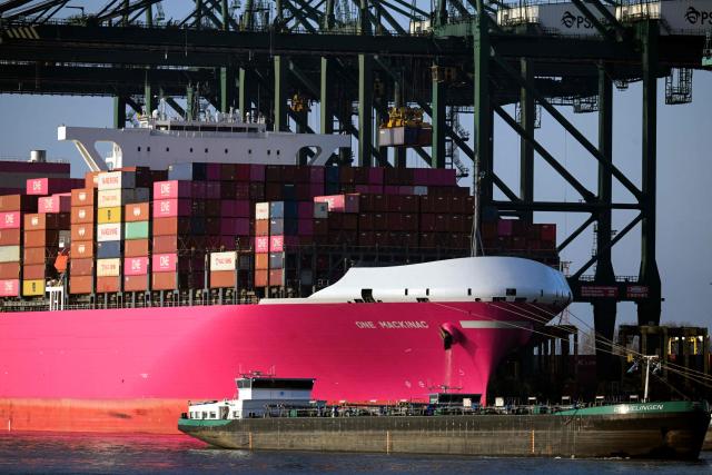 A barge sails past the Japanese "One Mackinac" container ship docked in the Port of Antwerp-Bruges, in Antwerp, on November 21, 2025. (Photo by Nicolas TUCAT / AFP)