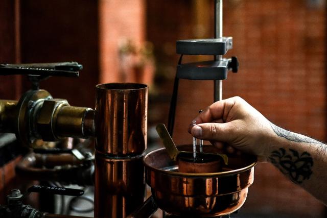 A distiller uses an alcoholometer to measure the alcohol content of a brandy sample flowing from stills during the Cognac brandy distillation process at the Chateau Montifaud wineries in Jarnac-Champagne, Cognac region, southwestern France, on November 21, 2025. Owned by the same family for six generations, Chateau Montifaud has been producing Cognac brandy since the early 19th century on a 150-hectare estate located just south of Cognac. (Photo by Christophe ARCHAMBAULT / AFP)