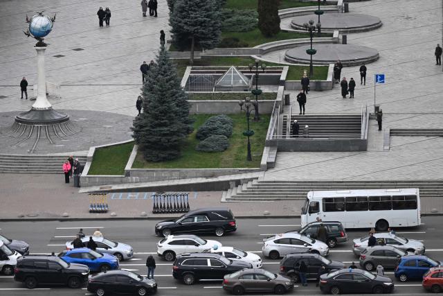 Pedestrians and drivers observe a minute of silence as the body of a slain Ukrainian soldier is carried in a hearse on past Independence Square, in Kyiv, on November 24, 2025, amid the Russian invasion of Ukraine. Ukrainian President Volodymyr Zelenky on November 24, 2025 hailed "important steps" after talks in Geneva with the US, but said more work is needed to negotiate an end to the war with Russia. (Photo by Sergei GAPON / AFP)