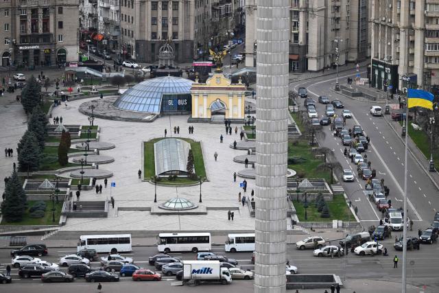 Pedestrians and drivers observe a minute of silence as the body of a slain Ukrainian soldier is carried in a hearse (L) past Independence Square, in Kyiv, on November 24, 2025, amid the Russian invasion of Ukraine. Ukrainian President Volodymyr Zelenky on November 24, 2025 hailed "important steps" after talks in Geneva with the US, but said more work is needed to negotiate an end to the war with Russia. (Photo by Sergei GAPON / AFP)
