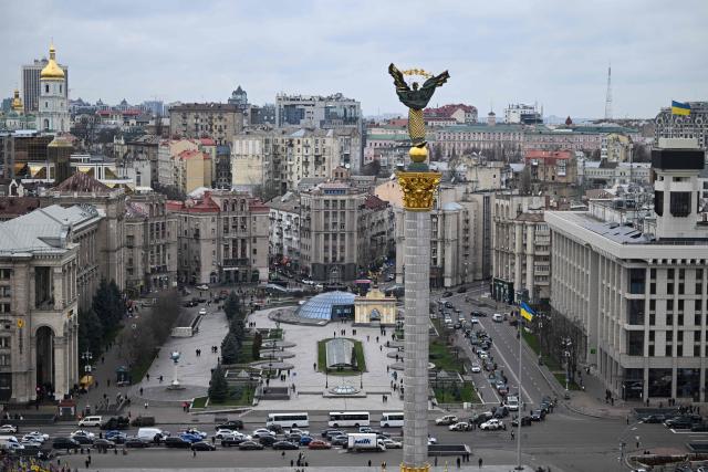 Pedestrians and drivers observe a minute of silence as the body of a slain Ukrainian soldier is carried in a hearse past Independence Square, in Kyiv, on November 24, 2025, amid the Russian invasion of Ukraine. Ukrainian President Volodymyr Zelenky on November 24, 2025 hailed "important steps" after talks in Geneva with the US, but said more work is needed to negotiate an end to the war with Russia. (Photo by Sergei GAPON / AFP)