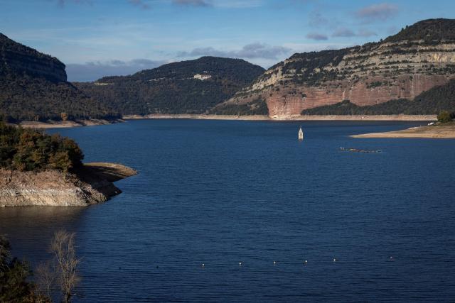 This photograph taken on November 24, 2025 shows the partially submerged bell tower of the old church of Sant Roma de Sau, in the reservoir of Sau in Vilanova de Sau in Catalonia. This long-Term project shows an inventory of several sites in Spain which are suffering from drought. Photos of the same places are taken every month over a very long period. (Photo by Josep LAGO / AFP)