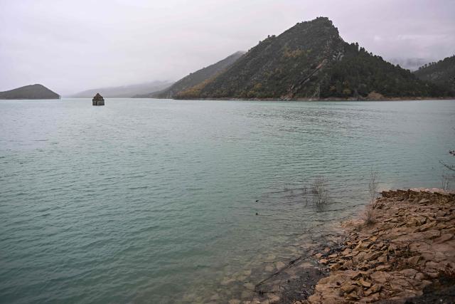 This photograph taken on November 24, 2025 shows a view of the Mediano reservoir, with the Church of Asuncion of Mediano partially visible, in Mediano, Huesca province. This long-term project shows an inventory of several sites in Spain which are suffering from drought. Photos of the same places are taken every month over a very long period. (Photo by ANDER GILLENEA / AFP)