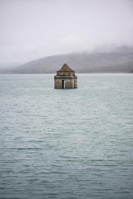 This photograph taken on November 24, 2025 shows a view of the Mediano reservoir, with the Church of Asuncion of Mediano partially visible, in Mediano, Huesca province. This long-term project shows an inventory of several sites in Spain which are suffering from drought. Photos of the same places are taken every month over a very long period. (Photo by ANDER GILLENEA / AFP)
