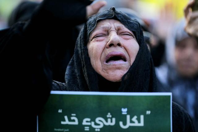 A mourner holds a placard that reads in Arabic: "Everything has its limits", during the funeral of top Hezbollah chief Haytham Ali Tabatabai and others killed in an Israeli strike a day earlier, in Beirut’s southern suburbs on November 24, 2025. Hezbollah held the funeral on November 24 for its top military chief and other members of the militant group a day after Israel killed them in a strike on Beirut's southern suburbs. (Photo by Ibrahim AMRO / AFP)
