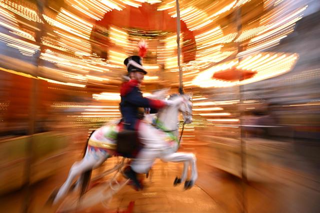 A youth in a costume sits on a merry-go-round at the Christmas market at the central Roemer square in Frankfurt am Main, on November 24, 2025. (Photo by Kirill KUDRYAVTSEV / AFP)