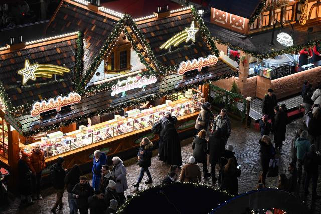 People pass by a candy selling booth at the Christmas market at the central Roemer square in Frankfurt am Main, on November 24, 2025. (Photo by Kirill KUDRYAVTSEV / AFP)