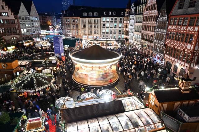 A merry-go-round is pictured among booths at the Christmas market at the central Roemer square in Frankfurt am Main, on November 24, 2025. (Photo by Kirill KUDRYAVTSEV / AFP)