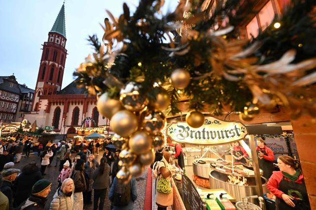 People walk around the Christmas market at the central Roemer square in Frankfurt am Main, on November 24, 2025. (Photo by Kirill KUDRYAVTSEV / AFP)