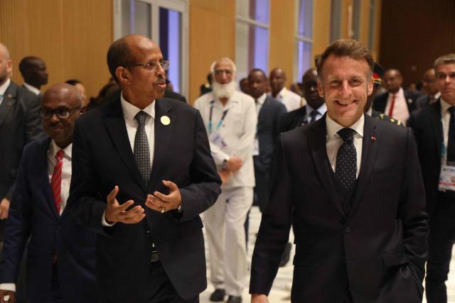 African Union Commission Chairperson Mahamoud Ali Youssouf (L) gestures as he walks with President of France Emmanuel Macron (R) at the Africa Union (AU) - European Union (EU) Summit the Salao Protocolar in Luanda on November 24, 2025. (Photo by Ludovic MARIN / AFP)