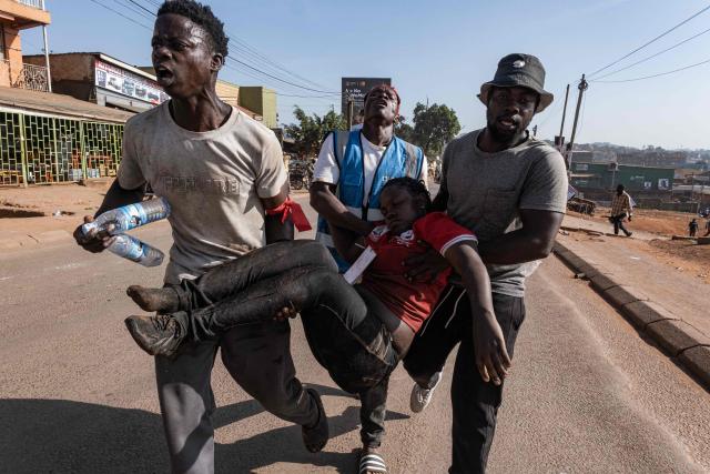 EDITORS NOTE: Graphic content / TOPSHOT - Supporters of National Unity Platform (NPU) presidential candidate and opposition leader Robert Kyagulanyi, also known as Bobi Wine, carry an injured woman after tear gas is fired by Ugandan police officers during a dispersal operation following his presidential campaign rally in Kampala, on November 24, 2025. Bobi Wine, the main challenger to President Yoweri Museveni's 40-year rule in Uganda, drew vast crowds as he brought his campaign to the capital Kampala on November 24, 2025 ahead of January's election.
Wine, whose real name is Robert Kyagulanyi, is a 43-year-old singer turned politician who has become hugely popular among Ugandan young people but faces a deeply entrenched political machine led by the 81-year-old Museveni. (Photo by Badru Katumba / AFP)