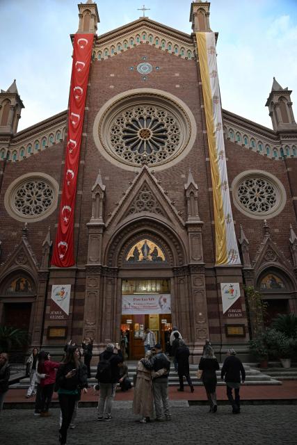 People visit the Saint Anthony of Padua Church as a welcome banner bearing a portrait of Pope Leo XIV is displayed on its gate, ahead of his visit to Turkey, in Istanbul on November 24, 2025. (Photo by Ozan KOSE / AFP)