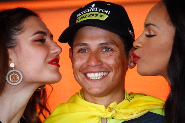 (FILES) Hostesses kiss Team Mitchelton rider Colombia's Esteban Chaves celebrates on the podium after winning stage nineteen of the 102nd Giro d'Italia - Tour of Italy - cycle race, 151kms from Treviso to San Martino di Castrozza on May 31, 2019. After 16 years in the world elite, Chaves is retiring from professional cycling, his current team, Team Education First, announced on social media on November 24, 2025. (Photo by Luk BENIES / AFP)