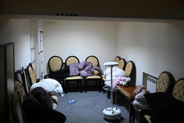 People lie on chairs in the hotel's underground shelter during an air attack in Kyiv early on November 25, 2025, amid the Russian invasion of Ukraine. Powerful explosions rocked Ukraine's capital Kyiv, an AFP journalist heard, as the air force issued a countrywide missile warning early November 25, 2025. (Photo by Sergei GAPON / AFP)