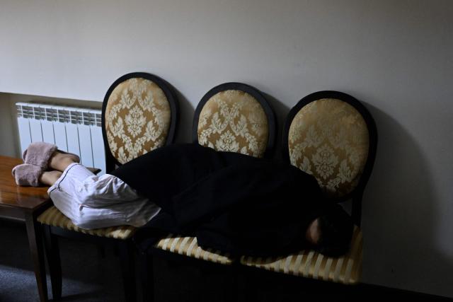A woman lies on chairs in the hotel's underground shelter during an air attack in Kyiv early on November 25, 2025, amid the Russian invasion of Ukraine. Powerful explosions rocked Ukraine's capital Kyiv, an AFP journalist heard, as the air force issued a countrywide missile warning early November 25, 2025. (Photo by Sergei GAPON / AFP)