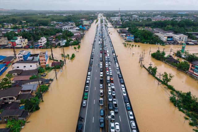 TOPSHOT - This aerial photo taken on November 25, 2025 shows vehicles parked on an elevated road to keep them out of flood waters in Hat Yai in Thailand's southern Songkhla province, as severe flooding affected thousands of people in the country's south following days of heavy rain. (Photo by Arnun Chonmahatrakool / THAI NEWS PIX / AFP)