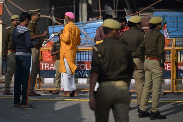 A Hindu devotee interacts with a policeman near Ram Temple in Ayodhya on November 25, 2025, ahead of Indian Prime Minister Narendra Modi’s visit. (Photo by Sajjad  HUSSAIN / AFP)