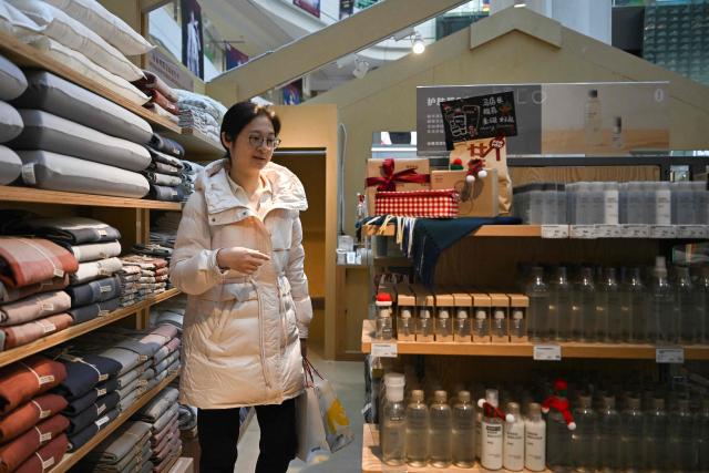 A woman shops at a Muji store branch in Beijing on November 25, 2025. (Photo by Pedro PARDO / AFP)