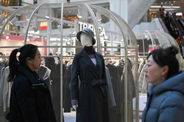 People are seen at a shopping mall in Beijing on November 25, 2025. (Photo by Pedro PARDO / AFP)