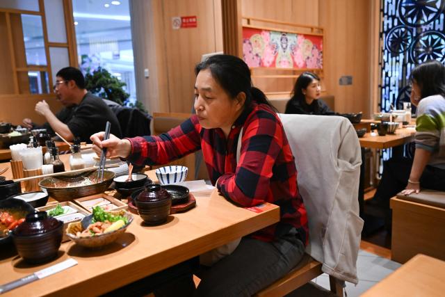 People have lunch at a branch of the Japanese restaurant chain Saboten in Beijing on November 25, 2025. (Photo by Pedro PARDO / AFP)