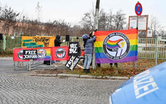 Demonstrators protest prior to the start of a trial of seven accused left extremists for membership in a criminal organisation on November 25, 2025 at the Higher Regional Court of Dresden, eastern Germany. The seven defendants are alleged members of the 'Antifa East' gang suspected of attacks on right-wing extremist. (Photo by MATTHIAS RIETSCHEL / POOL / AFP)