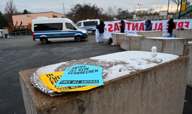 Demonstrators protest prior to the start of a trial of seven accused left extremists for membership in a criminal organisation on November 25, 2025 at the Higher Regional Court of Dresden, eastern Germany. The seven defendants are alleged members of the 'Antifa East' gang suspected of attacks on right-wing extremist. (Photo by MATTHIAS RIETSCHEL / POOL / AFP)