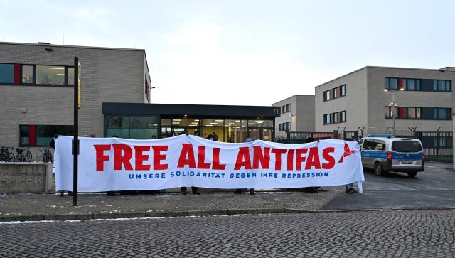 Demonstrators protest prior to the start of a trial of seven accused left extremists for membership in a criminal organisation on November 25, 2025 at the Higher Regional Court of Dresden, eastern Germany. The seven defendants are alleged members of the 'Antifa East' gang suspected of attacks on right-wing extremist. (Photo by MATTHIAS RIETSCHEL / POOL / AFP)
