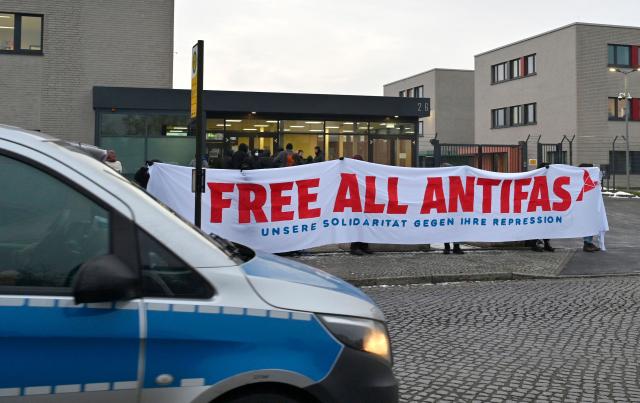 Demonstrators protest prior to the start of a trial of seven accused left extremists for membership in a criminal organisation on November 25, 2025 at the Higher Regional Court of Dresden, eastern Germany. The seven defendants are alleged members of the 'Antifa East' gang suspected of attacks on right-wing extremist. (Photo by MATTHIAS RIETSCHEL / POOL / AFP)