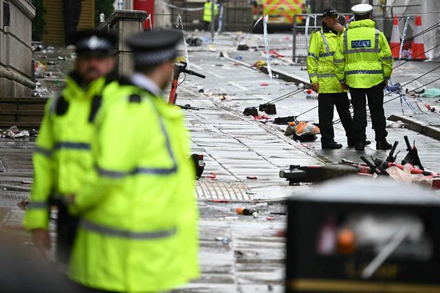 (FILES) Police officers work at the scene on Water Street in Liverpool, north-west England on May 27, 2025, after a car on May 26, ploughed in to crowds that had gathered to watch an open-top bus victory parade for Liverpool's Premier League trophy parade. A British man is due to go on trial on November 25, 2025 accused of driving his car into crowds at Liverpool Football Club's Premier League victory parade in May and injuring dozens of people. Paul Doyle, 54, has pleaded not guilty to 31 alleged offences, including charges of causing grievous bodily harm (GBH) with intent, wounding with intent, affray and dangerous driving. (Photo by Paul ELLIS / AFP)