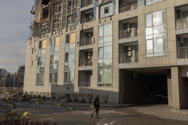 A pedestrian walks past a damaged residential building following Russian missiles and drones strikes in Kyiv on November 25, 2025, amid Russian invasion in Ukraine. Russia rained missiles and drones overnight on Kyiv, killing six people, authorities said on November 25, 2025, as three people died in Russia's Rostov region in massive Ukrainian strikes. (Photo by Roman PILIPEY / AFP)