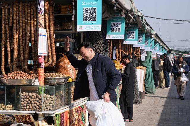 A customer reacts as digital cashless payment QR (quick response) codes are displayed at a market in Islamabad on November 25, 2025. (Photo by Farooq NAEEM / AFP)